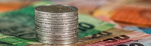 silver coins stacked on colorful 
bills