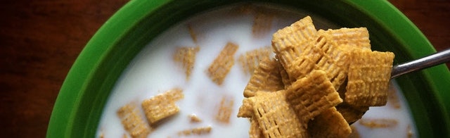 spoon lifting 
cereal in milk out of a green bowl