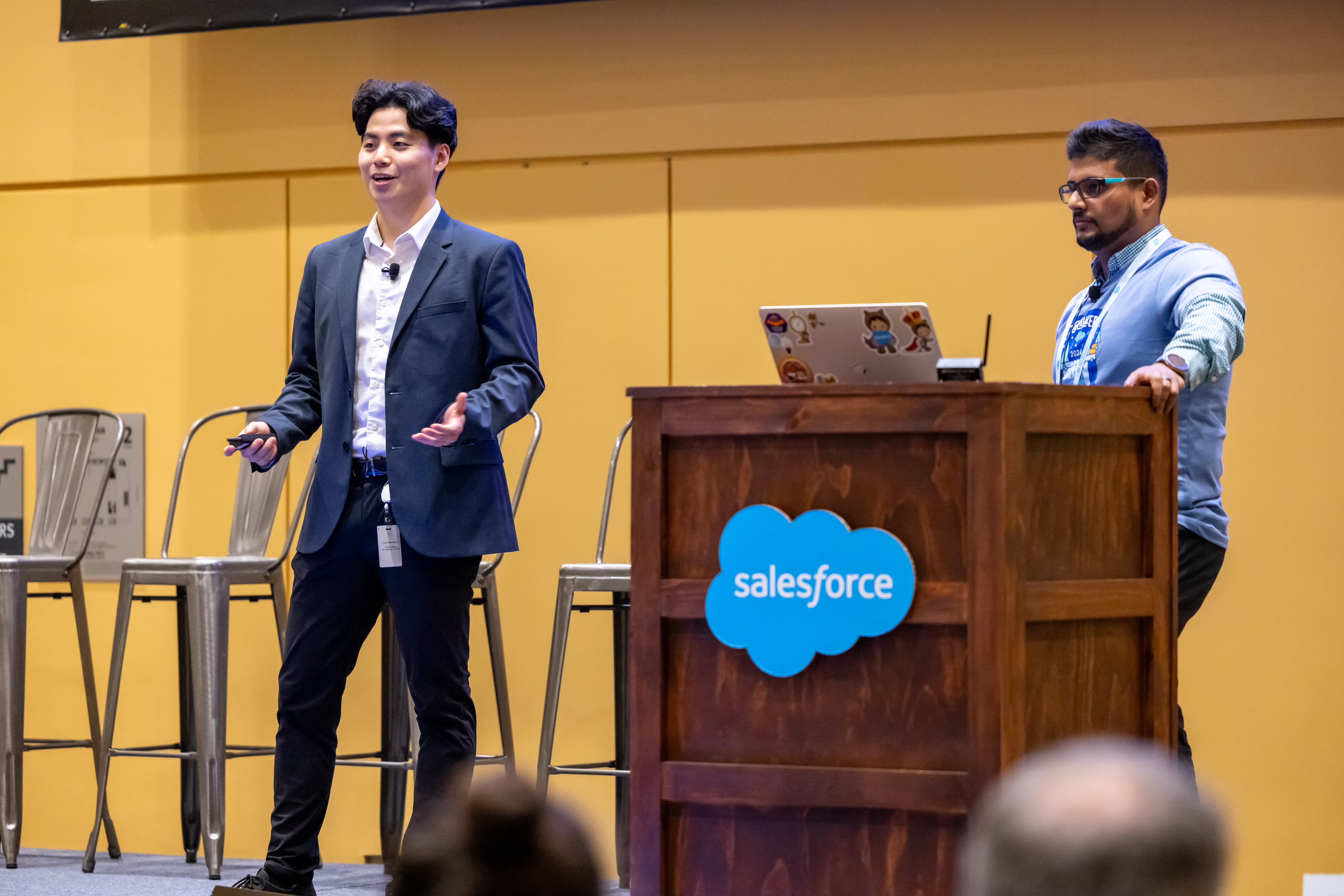 Kevin Qi speaking on stage at a Salesforce event.