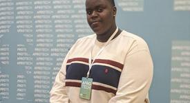 Earl Potts sits on a golden couch at the AfroTech Conference for Black students in computer science