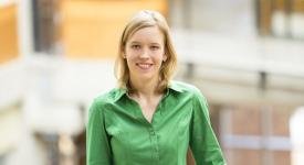 Franzi Roesner, TXCS alumnus, White woman with blonde hair in green button down shirt standing in front of a building smiling