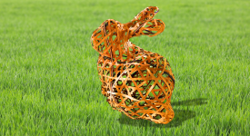 Woven, lattice-like rabbit sculpture made of brown wooden strips, positioned on green grass with a soft, blurred background.