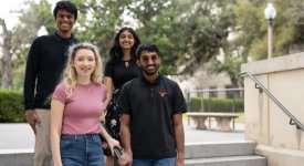 Four undergraduate students, Prasann Singhal, Nihita Sarma, Shankar Padmanabhan and Jennifer Mickel pose on a staircase near a limestone building at UT.