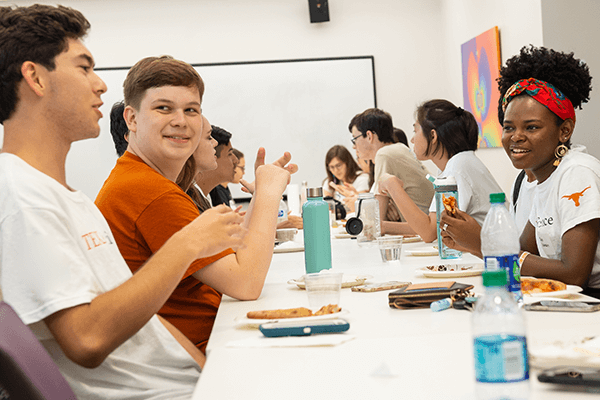 A group of students sitting at a table, eating and talking together