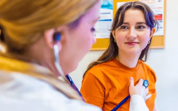Healthcare professional using a stethoscope to listen to a patient's chest during a medical exam