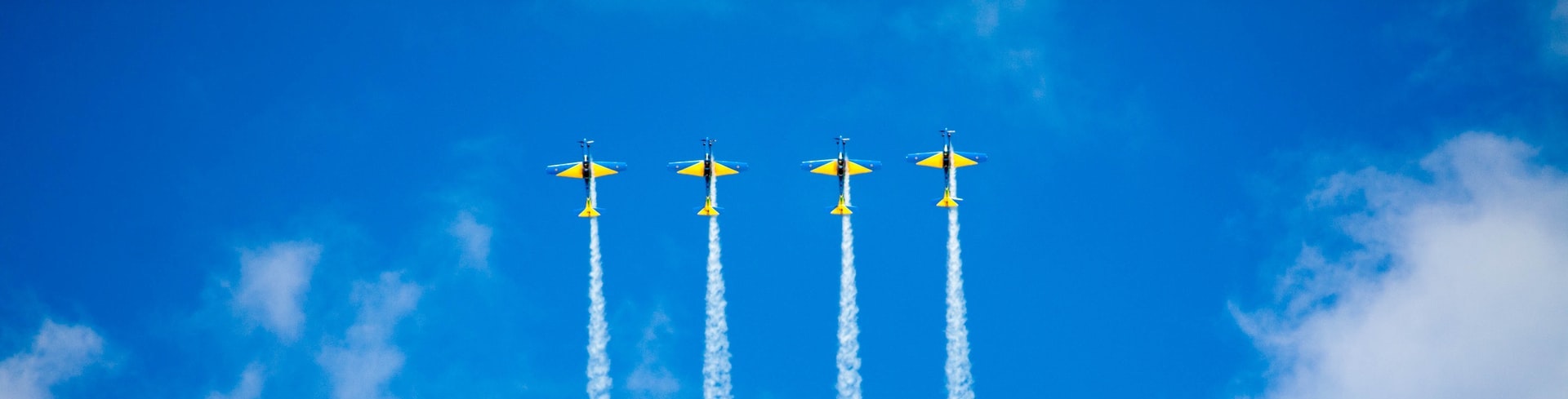 Synchronized yellow planes fly in a blue sky by Gabriel Gusmao on Unsplash