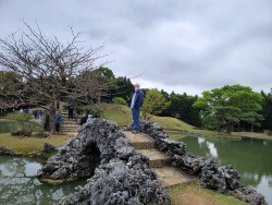 Alan standing on a small bridge in a garden.